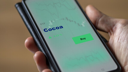 An investor's analyzing the cocoa etf fund on screen. A phone shows the ETF's prices food commodities to invest in cacao traded.