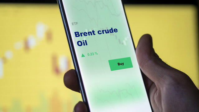 An investor's analyzing the brent crude diesel etf fund on screen. A phone shows the brent crude ETF's prices uls oil energy to invest