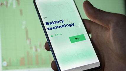 An investor's analyzing the battery technology etf fund on screen. A phone shows the batteries ETF's prices to invest.