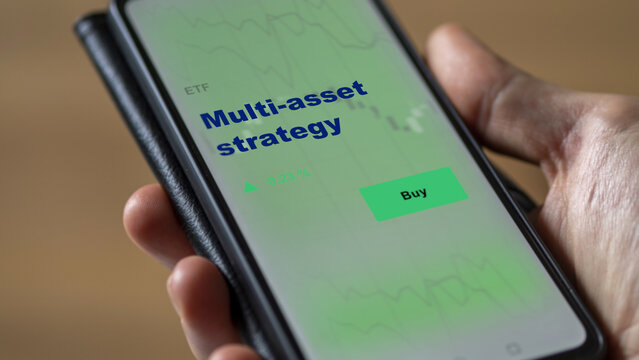An Investor's Analyzing The Multi-asset Strategy Etf Fund On Screen. A Phone Shows The ETF's Prices Multi Asset Strategy To Invest