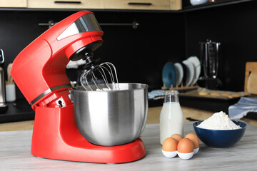 Modern stand mixer and ingredients on wooden table in kitchen. Home appliance
