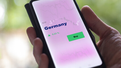 An investor's analyzing the Germany etf fund on screen. A phone shows the ETF's prices germany German greek to invest