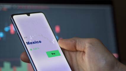 An investor's analyzing the Mexico etf fund on screen. A phone shows the ETF's prices Mexican mexican mexica to invest