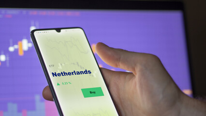 An investor's analyzing the Netherlands etf fund on screen. A phone shows the ETF's prices Holland to invest