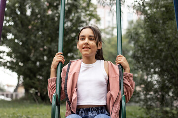 Close-up portrait of smiling girl on a swing.