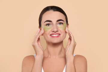 Beautiful woman with under eye patches on beige background