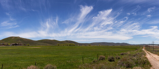 Cloudscape over the green fields in a city during sunny day. Evanston, Wyoming, United States of...
