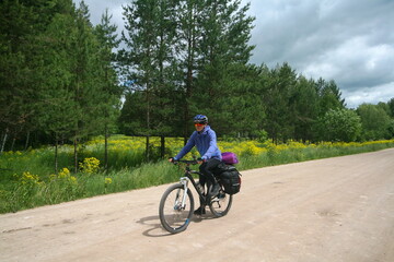 Naklejka premium A cyclist rides on a road among fields, Bashkortostan, Russia.