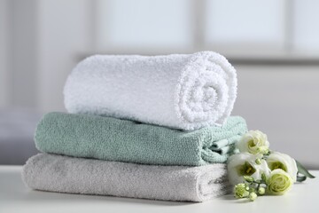 Stack of folded colorful towels with flowers on white table indoors, closeup