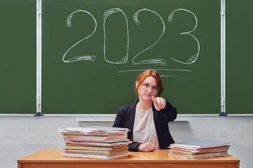 School teacher points a finger forward, blackboard with the text 2023 year