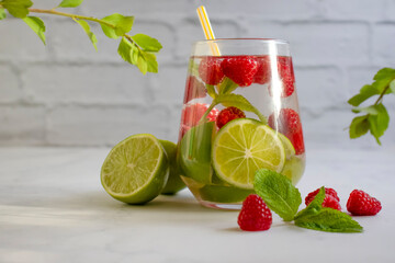 Glass with lime, raspberries, mint on a light background