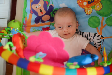 Newborn baby playing on the baby gym playmat