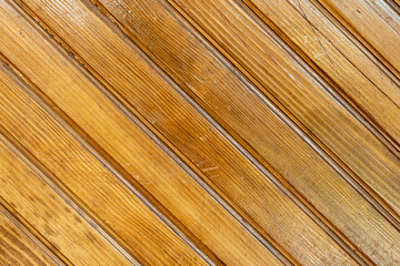 Brown background texture of a wooden fence made of diagonal planks of natural wood. Wooden background from wooden planks.