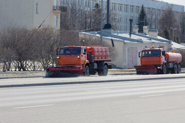 Two trucks with water tanks clear the roadway with snow plows