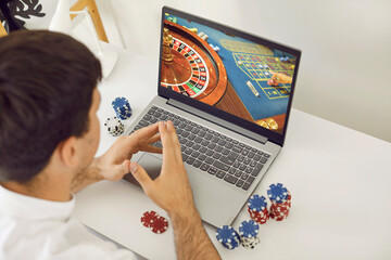 Young man playing poker on an online casino club website. Young guy sitting at a desk with poker...