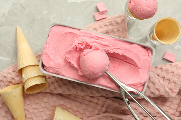 Delicious ice cream in container and wafer cones on light grey table, flat lay
