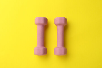 Stylish dumbbells on yellow background, flat lay
