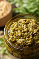 Jar of tasty arugula pesto on table, closeup