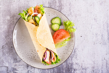 Mexican tortilla wraps with  vegetables and chicken on a plate on the table. Top view. Closeup