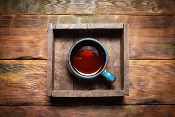 Cup of black hot tea on the wooden kitchen table background. Top view.
