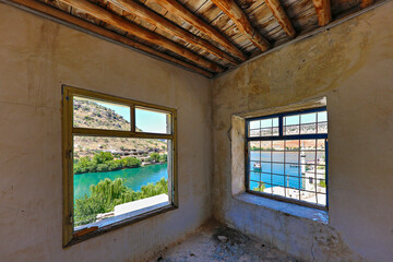 Euphrates river and the minaret that remained under the water of Birecik Dam through the windows of an abandoned house in Halfeti, Turkey