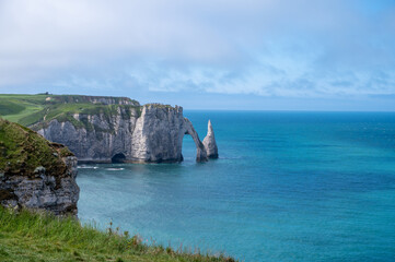 Panoramic view on chalk cliffs and Porte d'Aval arch in Etretat, Normandy, France. Tourists destination.
