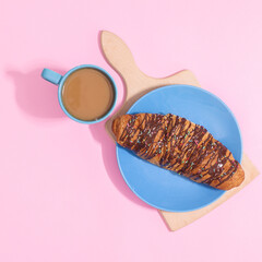 Fresh delicious croissant with cup of coffee on pastel pink background. Flat lay