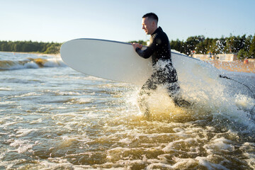 A male surfer learns to ride a surfboard on the waves