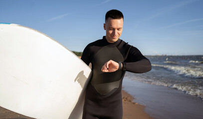 Uses a waterproof watch a surfer man in a wetsuit learns to surfboard in the sea on vacation