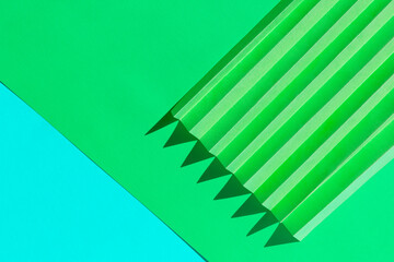 Abstract green and blue colored paper texture. Folded paper with harsh sun shadows, geometric shapes and lines. Minimalist background. Flat lay. Copy space.
