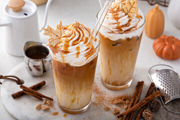 Iced pumpkin spice latte in tall glasses topped with whipped cream
