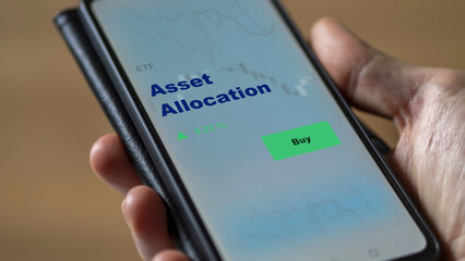 An investor's analyzing the asset allocation etf fund on screen. A phone shows the ETF's prices stocks to invest
