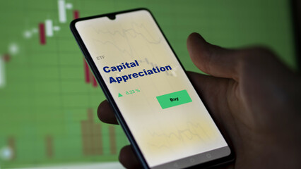 An investor's analyzing the capital appreciation etf fund on screen. A phone shows the ETF's prices capital appreciation to invest