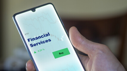 An investor's analyzing the financial Services etf fund on screen. A phone shows the ETF's prices financial services to invest