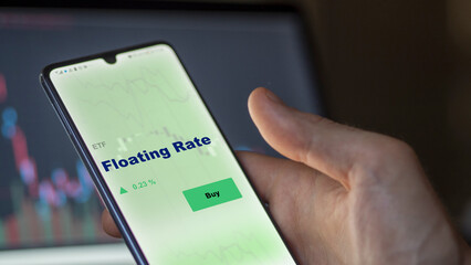 An investor's analyzing the floating Rate etf fund on screen. A phone shows the ETF's prices floating rate to invest