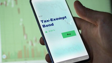 An investor's analyzing the tax-Exempt Bond etf fund on screen. A phone shows the ETF's prices tax exempt bond to invest