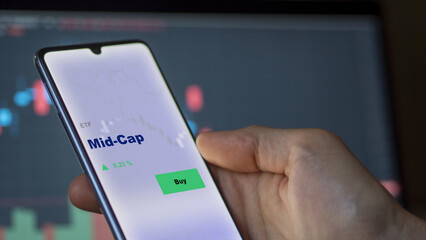 September 13th 2022, London UK. An investor's analyzing the mid-cap etf fund on screen. A phone shows the middle capitalization ETF's prices  to invest