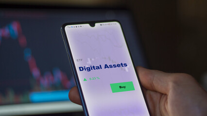 An investor's analyzing the digital assets etf fund on screen. A phone shows the ETF's prices stocks to invest