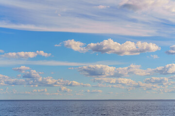 Naklejka na ściany i meble White clouds in the blue sky over the lake. Beautiful natural background.