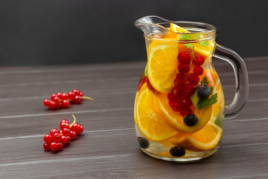 Redcurrant And Orange Infused Water In Glass Jug.