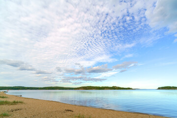 White clouds over the sandy shore of the lake in the sky. Beautiful natural background.