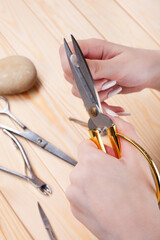 the hands of young woman cutting off long nails with big scissors