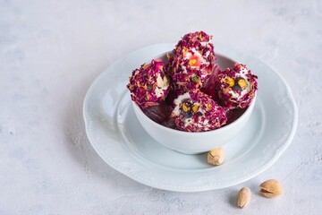 Oriental sweets, Turkish delight with rose petals and pistachios in a white bowl on a light concrete background.