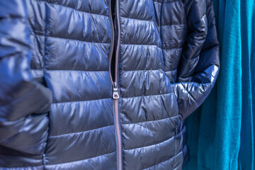 autumn-winter collection of clothes in the mall on the showcase blue down jacket shopping concept....
