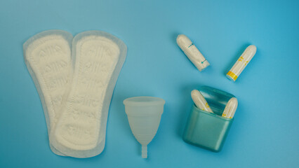 Menstruation products, pad, menstrual cup, tampon on a blue background. The view is flat. The concept of critical days, menstruation, women's health.
