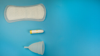 Menstruation products, pad, menstrual cup, tampon on a blue background. The view is flat. The concept of critical days, menstruation, women's health. copy space.