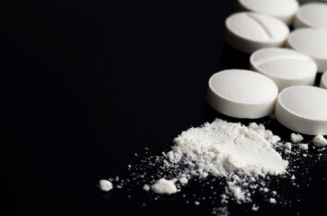 White powder and tablets on a black background