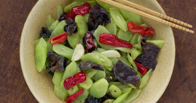 Stir fried celtuce (stem lettuce) with wood ear mushrooms (mun) top view, table spin.