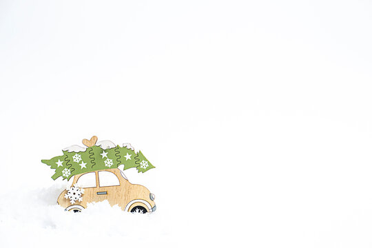Wooden toy car in a winter snow on white background. New year concept. Copy space