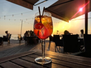 glass of fruit water  aperol on wooden  table on beach cafe at sunset on sea 